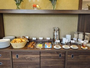 A buffet setup with bread, pastries, and various breakfast items. - Hotel Nordhausen (Nordhausen)