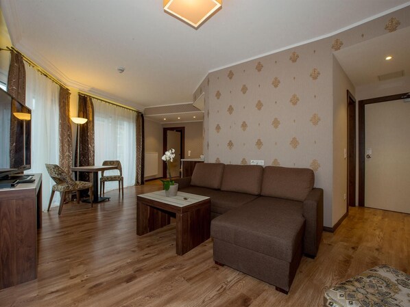 A living room with a sofa, a coffee table, a dining table with chairs, and a lamp.
