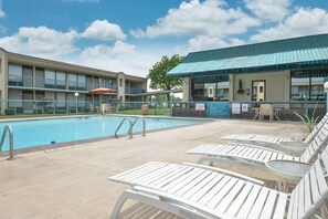 Un hôtel doté d’une piscine, de chaises longues et d’un espace salon abrité.
