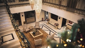A spacious lobby with a central seating area, a staircase, and a decorative chandelier. - Kyniska Palace Conference and Spa (Sparta)