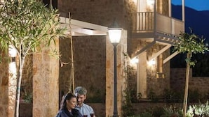 A couple sitting on a bench in a courtyard with a stone building and a balcony in the background. - Kyniska Palace Conference and Spa (Sparta)