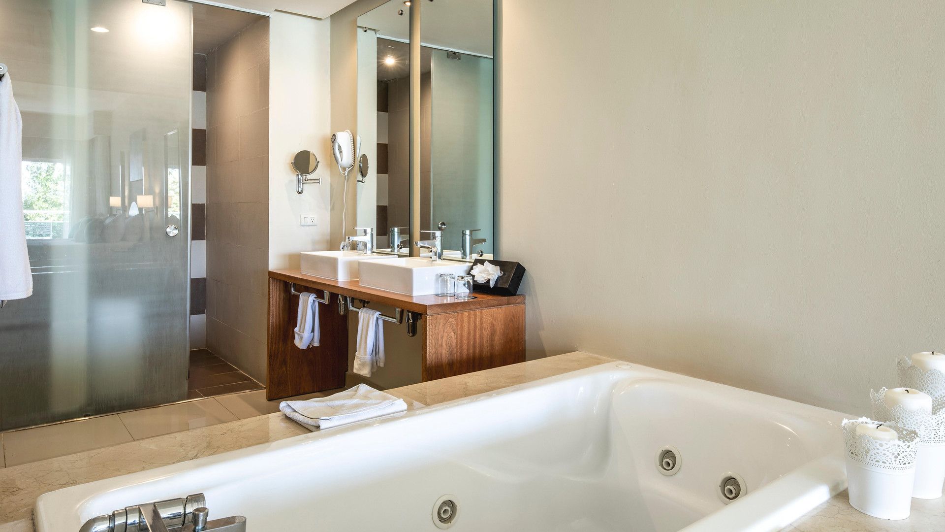 A modern bathroom with a large bathtub, dual sinks, and a glass shower enclosure.