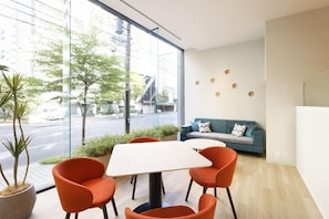 A modern interior with a large window, a sofa, orange chairs, and a table. - Tenza Hotel & Sky Spa Sapporo Central (Sapporo)