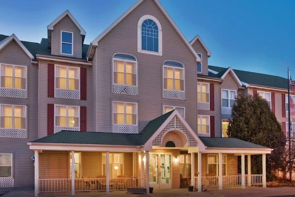 A multi-story hotel with a central entrance, multiple windows, and a covered front porch.