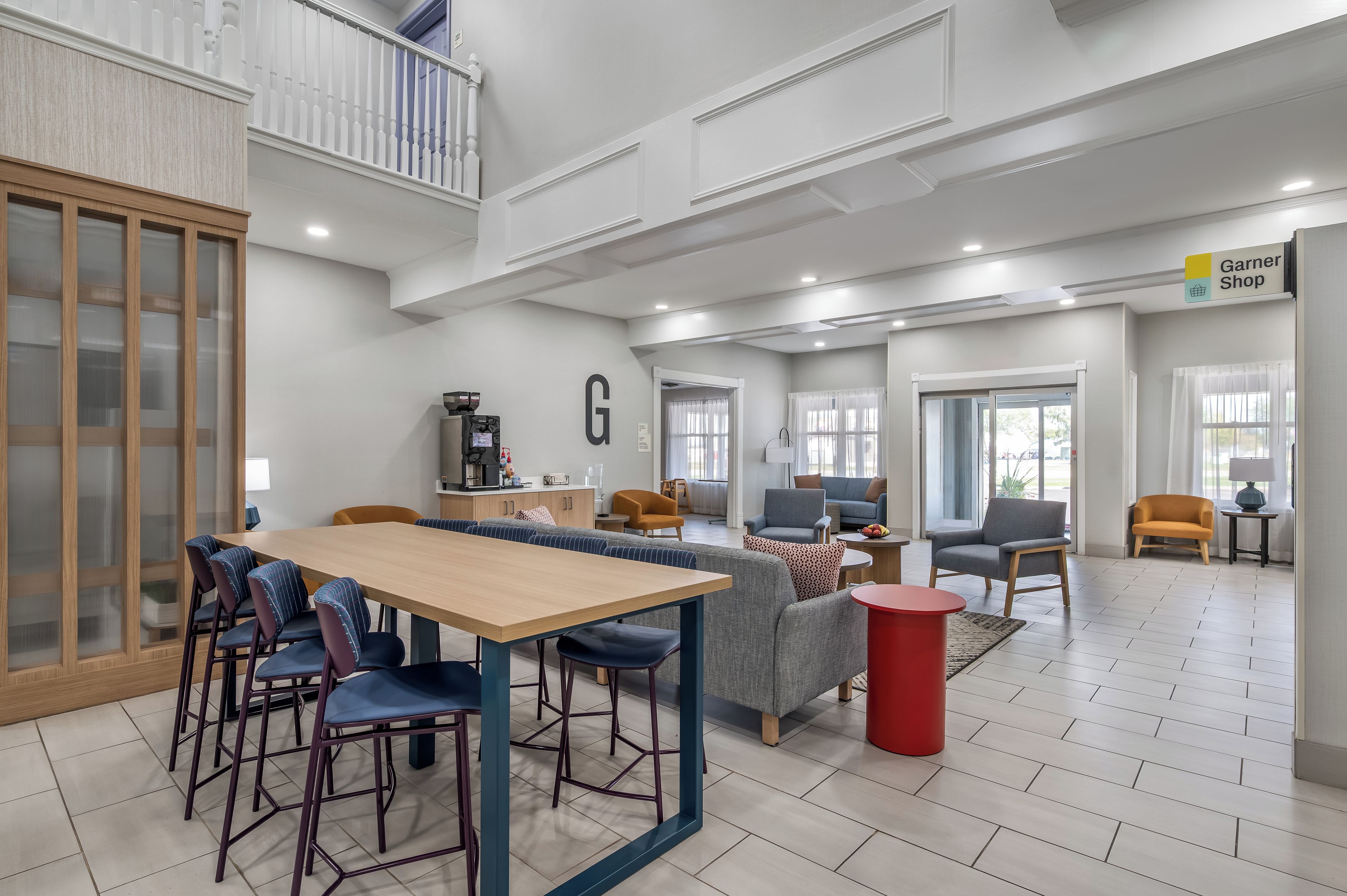 A spacious indoor area with a dining table, chairs, sofas, and a kitchen area.