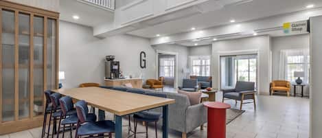 Un espacio interior amplio con una mesa de comedor, sillas, sofás y una zona de cocina.