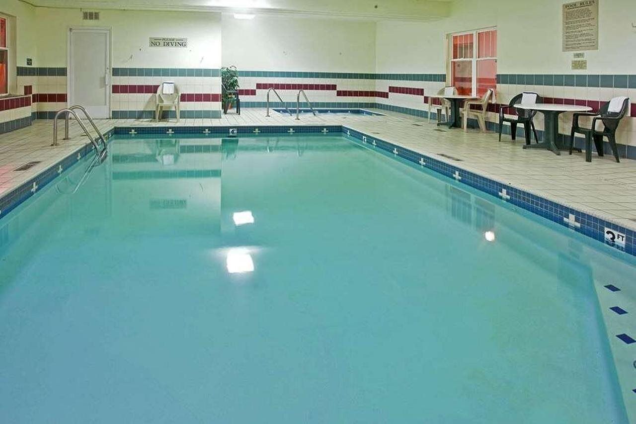 A swimming pool with a 'No Diving' sign, a ladder, and a seating area with tables and chairs.