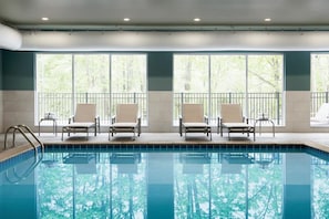 A swimming pool with four lounge chairs and large windows. - Country Inn & Suites by Radisson, Birch Run-frankenmuth, MI (Birch Run)