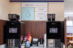 A coffee station with two coffee machines, a menu board, and various coffee-related items. - Country Inn & Suites by Radisson, Birch Run-frankenmuth, MI (Birch Run)
