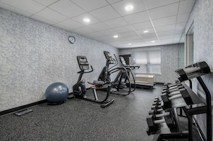 Un gimnasio con cintas de correr, elípticas, una bicicleta estática, una máquina de remo y pesas sueltas.