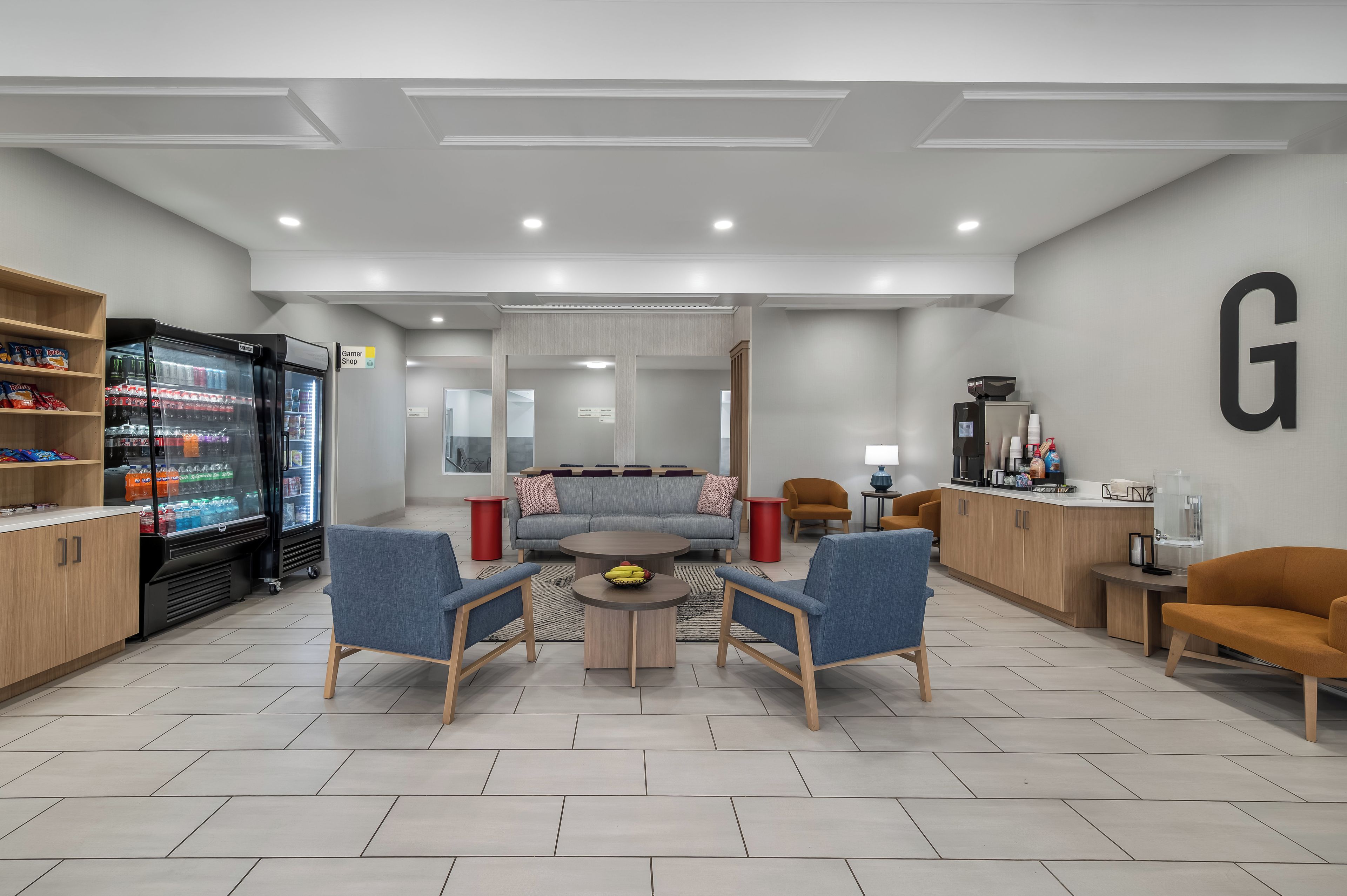 A modern lounge area with seating, a refreshment machine, and a visible 'Garner Shop' sign.