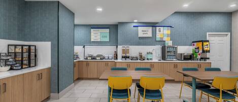 A modern kitchen with a central island, wooden cabinets, and a seating area with yellow chairs.