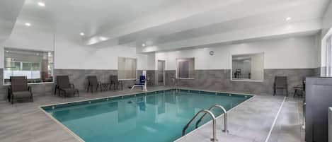 Une grande piscine intérieure avec un sol carrelé et un bord bleu.