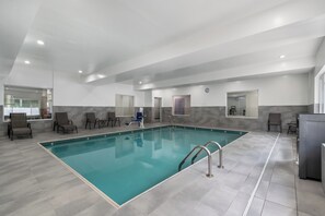 Ein großes Hallenbad mit gefliestem Boden und blauem Beckenrand.