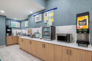 Un área de cocina moderna con cafetera, microondas y refrigerador.