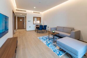 A modern living room with a sofa, a coffee table, and a dining area with chairs. - Beach Bay Hotel Mirfa, Edge by Rotana (Al Mirfa)