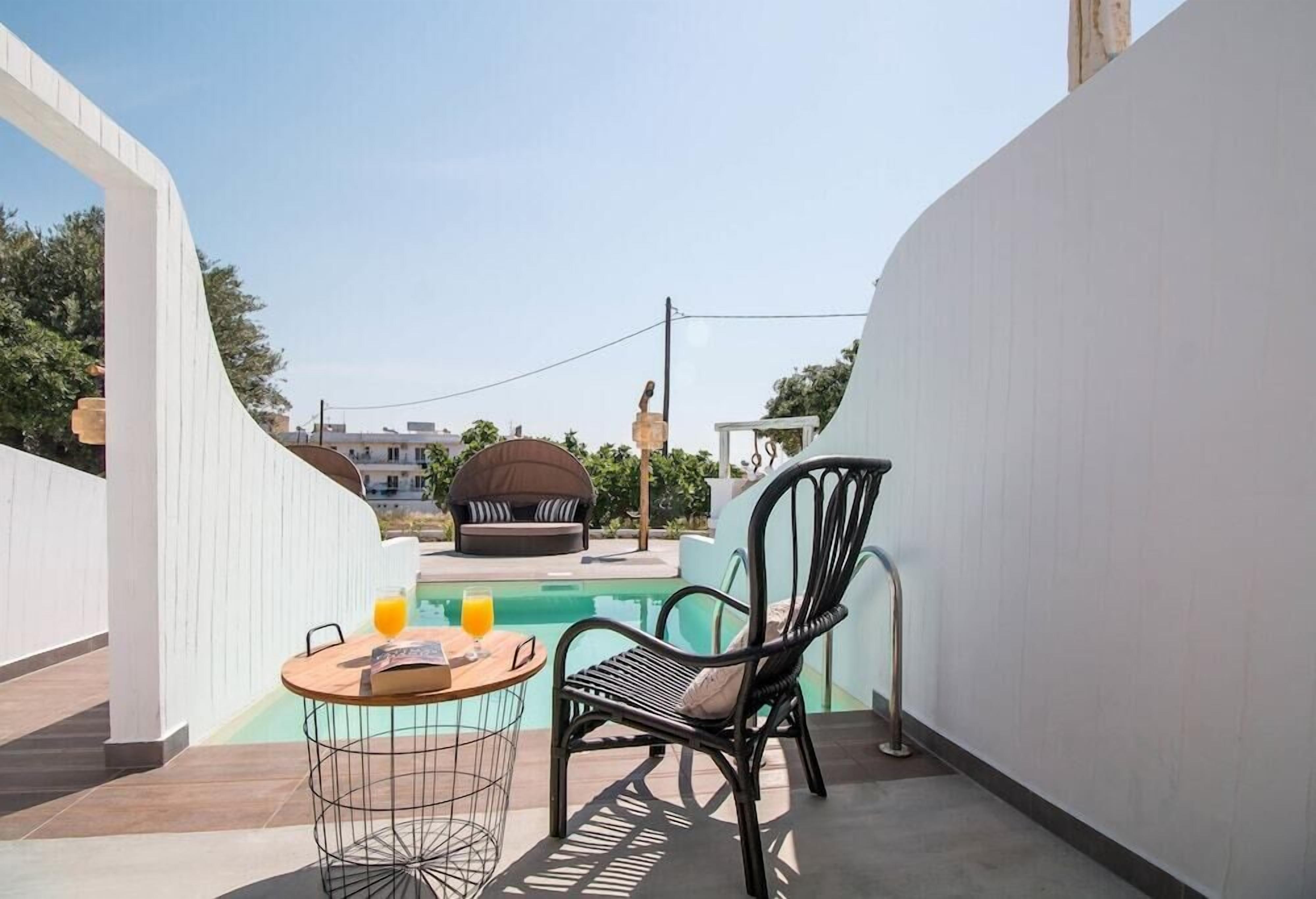 Un balcón con piscina, una mesa redonda con una silla y un sofá.
