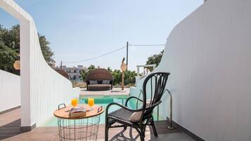 Un balcón con piscina, una mesa redonda con una silla y un sofá.
