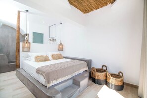 A modern bedroom with a bed, two hanging lights, a mirror, and two baskets. - Malibu Boutique Studios (Rhodes)