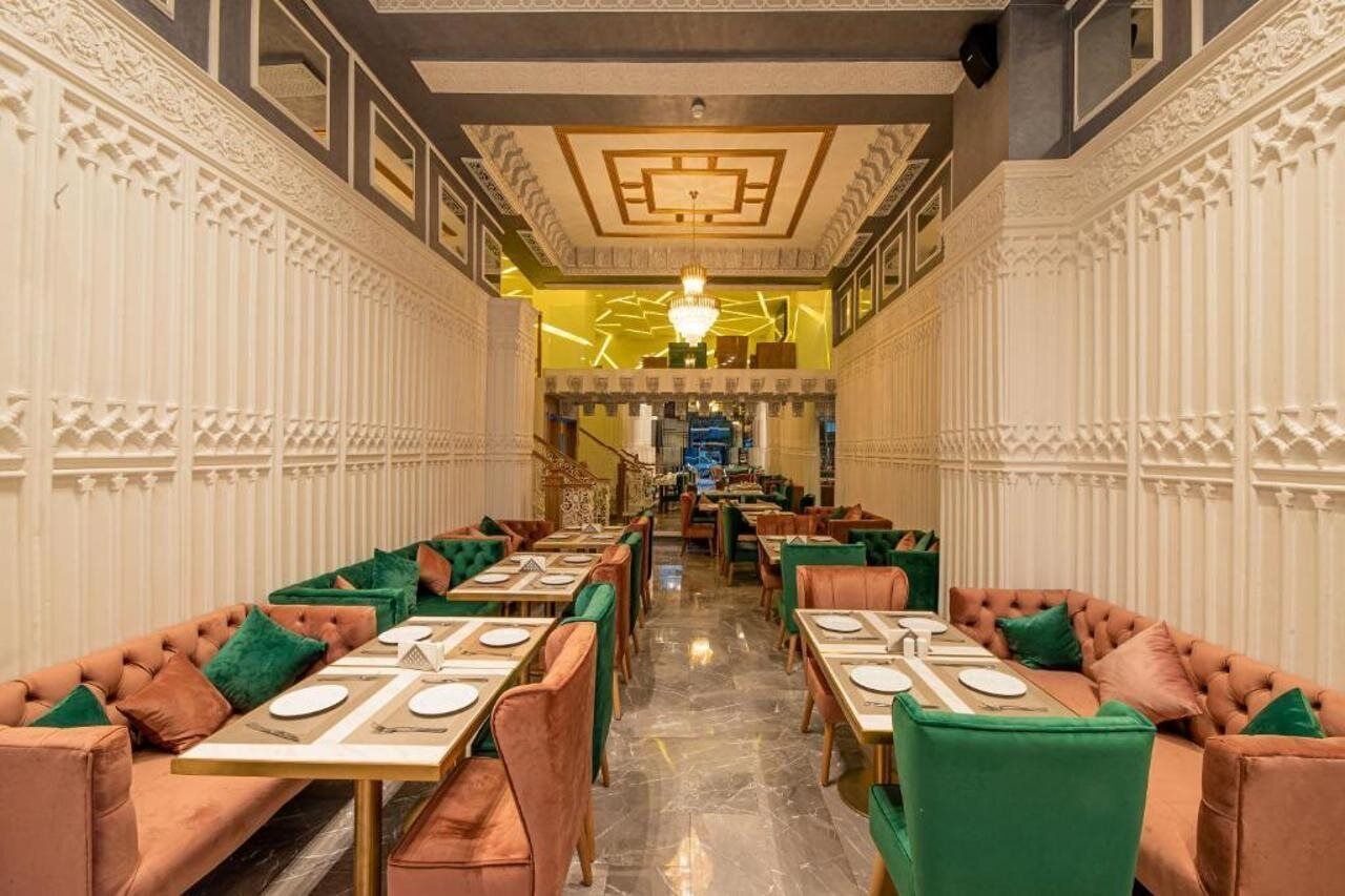 A restaurant with a central bar, booths, and a chandelier.