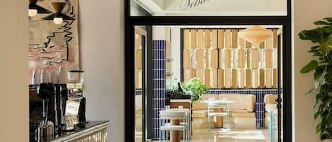 A modern interior with a cafe sign, a reception desk, and a seating area with a sofa and tables.