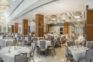 A spacious dining area with round tables, chairs, and a central bar area. - Fenix Hotel (Glyfada)