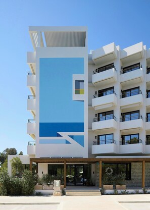 Ein modernes Hotel mit einer auffälligen blau-weißen Fassade, mehreren Balkonen und einem überdachten Eingangsbereich.