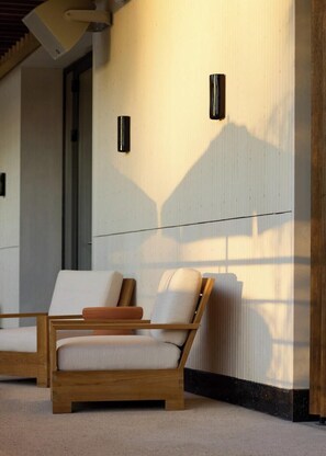 A modern room with two wooden-framed chairs, a white wall, and a radiator. - Fenix Hotel (Glyfada)