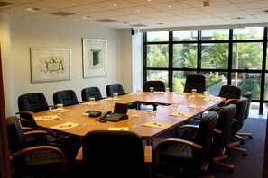 A conference room with a long table, black chairs, and framed artwork on the walls. - Fenix Hotel (Glyfada)
