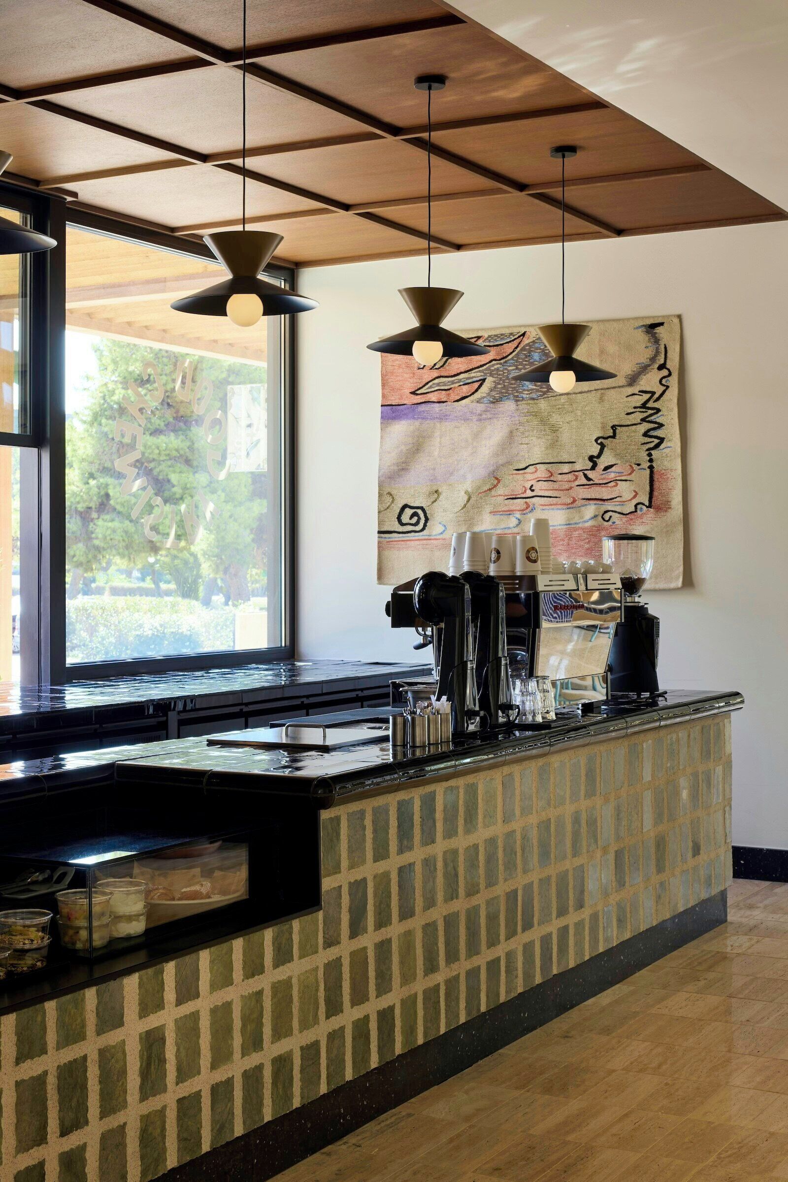 A coffee bar with a tiled backsplash, pendant lighting, and a coffee machine.