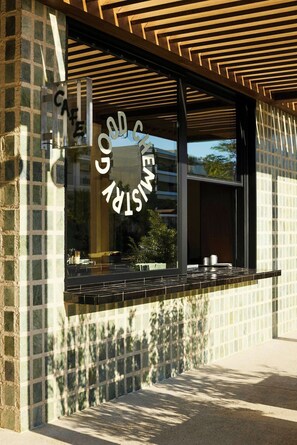 Una cafetería de diseño moderno, con un amplio ventanal y un letrero de metal.