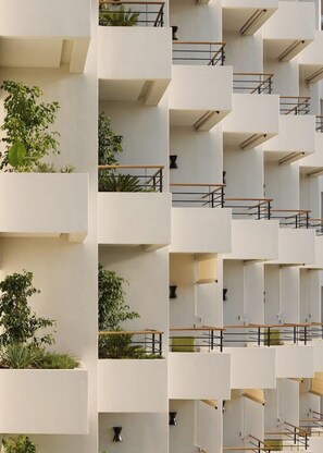 Un edificio de varios pisos con balcones, algunos adornados con plantas.