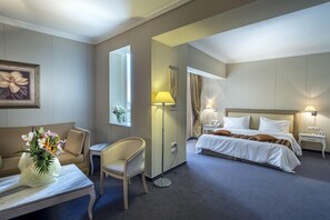 A hotel room with a bed, bedside tables, a desk, a chair, a lamp, and a mirror. - Fenix Hotel (Glyfada)