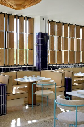 Un interior de restaurante moderno con paneles de madera, mesas redondas y asientos acolchados.