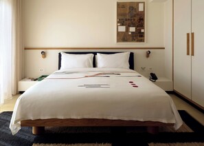 A hotel room with a bed, bedside table, lamp, and a wall-mounted artwork. - Fenix Hotel (Glyfada)