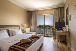 A hotel room with a bed, a desk, a television, and a balcony with a view. - Fenix Hotel (Glyfada)