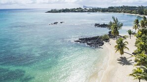 A tropical beach with clear turquoise water, a sandy shore, and palm trees.