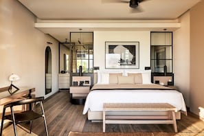 Quarto moderno com cama grande, mesas de cabeceira, escrivaninha e uma cadeira.