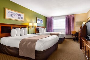 Ein Hotelzimmer mit zwei Betten, einem Fernseher, einem Schreibtisch und einem Fenster mit Vorhängen.