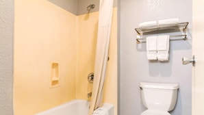 A bathroom with a bathtub, toilet, and towel rack. - Rodeway Inn Auburn, CA (Auburn)