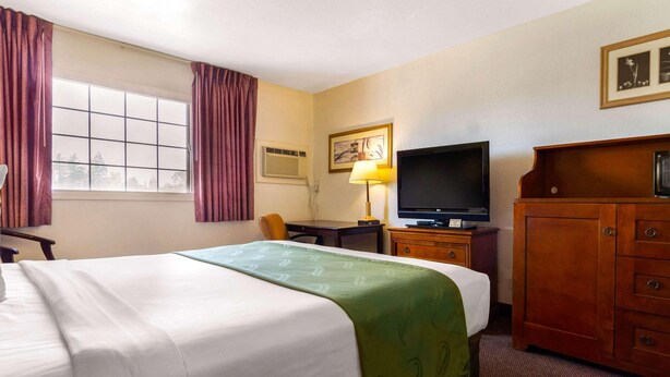 A hotel room with a bed, a desk, a television, and a cabinet. - Rodeway Inn Auburn, CA (Auburn)