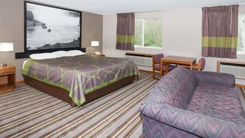 A hotel room with a bed, a desk, a chair, a sofa, a large window, and a wall-mounted TV.