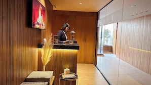 A reception area with a wooden interior, a receptionist, a reception desk, a small table with a book, and a large window. - Longue Vie Hotel Marrakech (Marrakech)