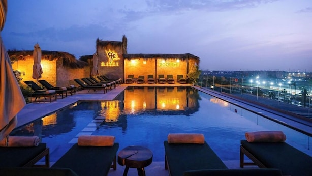 An infinity pool with lounge chairs and a view of the city at dusk. - Longue Vie Hotel Marrakech (Marrakech)