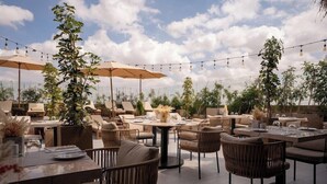 An outdoor dining area with round tables, chairs, and umbrellas. - Longue Vie Hotel Marrakech (Marrakech)