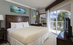A hotel room with a large bed, a desk, a chair, a TV, and a balcony with a view. - Secrets St. Lucia Resort & Spa Adults Only (Gros Islet)