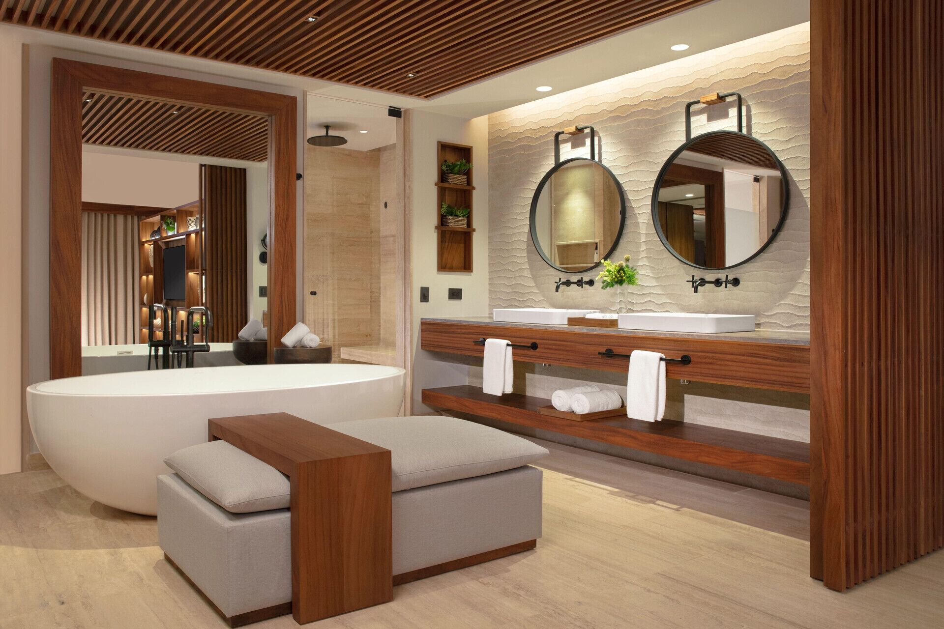 Un baño moderno con una bañera independiente, un tocador con un espejo grande y un banco de madera.