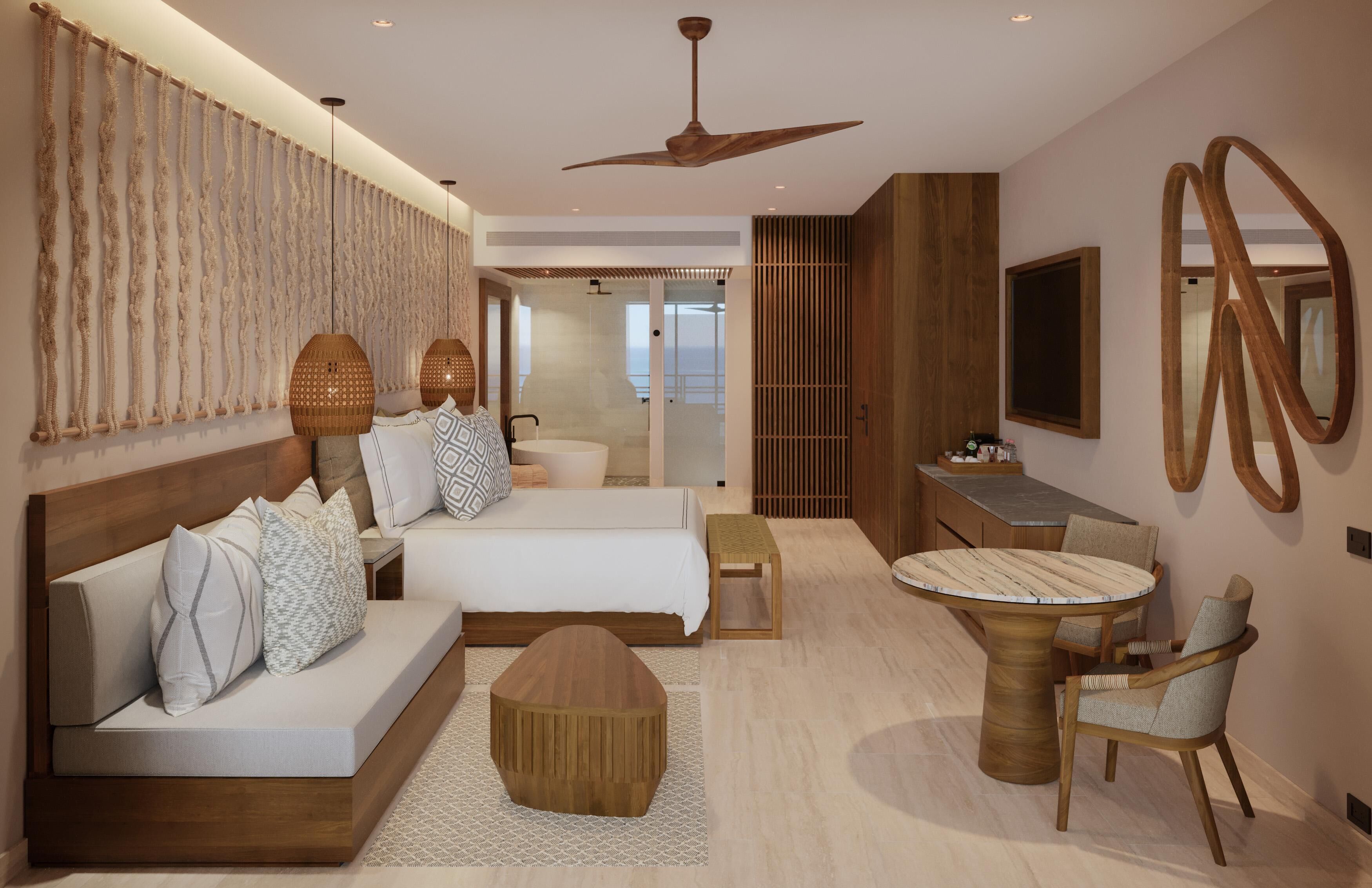 A modern hotel room with a bed, sofa, round table, and a TV mounted on the wall.