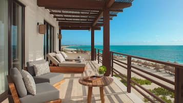Un balcon avec un canapé, une petite table et une vue sur l’océan.