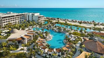 A resort with multiple swimming pools, beachfront, and a large building complex.